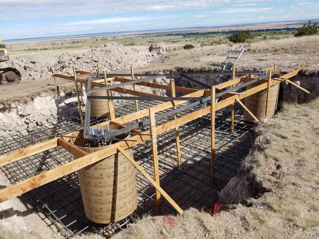 Tower foundation piers, anchor steel, and rebar on a ridge site