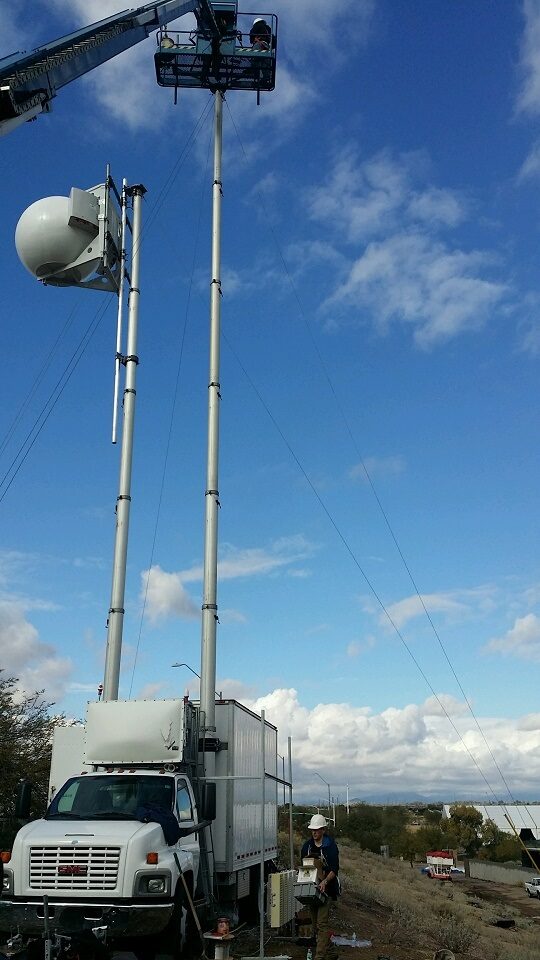 COLT truck with telescoping masts, microwave radome, and boom lift during temporary site installation